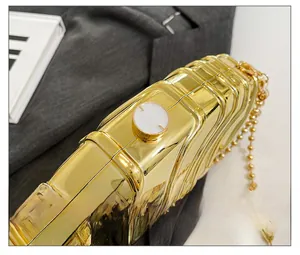 Detailed close-up of golden wavy evening bag with white disc clasp and metal chain