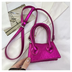 Detail of a mini metallic purple trapezoid handbag with a glossy finish and top handle