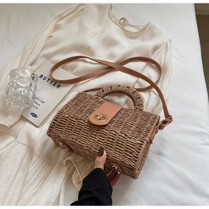 Detail of woven straw handbag with brown leather flap and gold metal twist-lock closure