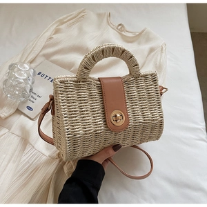 Detail of cream woven handbag featuring brown leather flap and metallic twist lock clasp