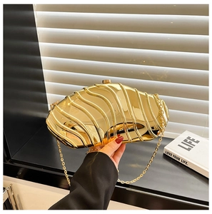 Detailed view of luxury gold acrylic clutch with wavy texture and metallic chain strap