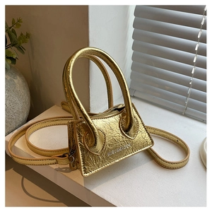 Close-up of gold crinkled leather mini bag with metal handles on a sunny windowsill