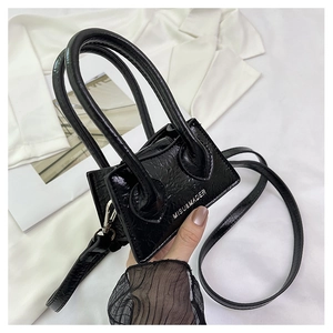 Detail of black mini crossbody bag featuring glossy crinkled leather and silver logo
