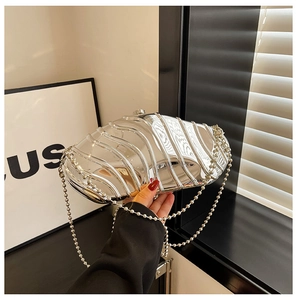 Detail view of a silver shell-shaped acrylic clutch bag with bead chain and metallic finish