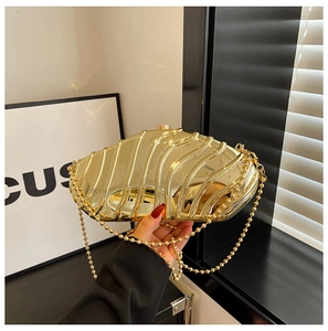 Macro shot of gold acrylic evening bag with wave texture and round bead chain