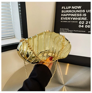 Macro detail of gold metal clutch bag featuring wave texture and polished mirror finish