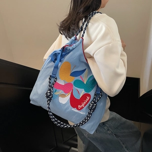 Light blue canvas drawstring backpack with colorful embroidered apples and braided ropes
