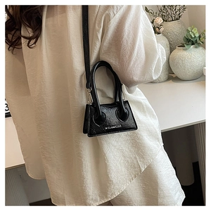 Black glossy patent leather mini trapezoid bag shown on model for size and detail