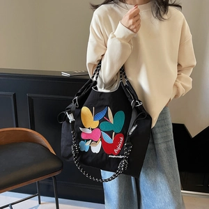 Canvas tote bag with colorful apple embroidery and woven straps for casual commuting