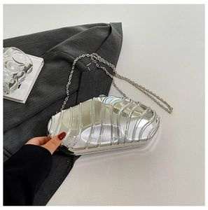 Macro shot of silver wavy textured evening clutch bag with elegant chain strap detail