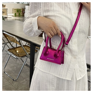 Close-up of mini rose pink crossbody bag with dual handles on white lace shirt