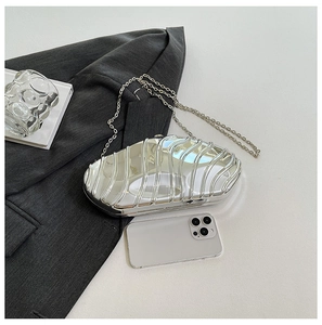 Detailed view of silver metallic shell clutch with fine chain on grey suit fabric