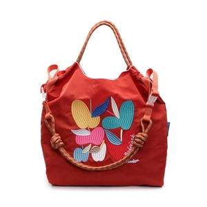 Red nylon tote bag with artistic apple embroidery and woven rope handles on white background
