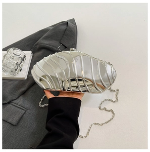 Detailed view of silver shell-shaped evening clutch bag with wavy metallic texture