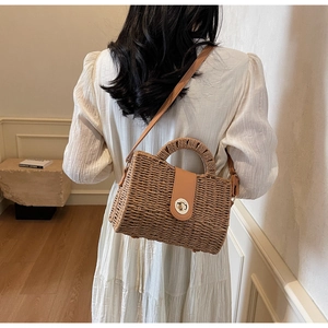 Detail view of a handmade straw crossbody bag with leather flap and metal twist lock