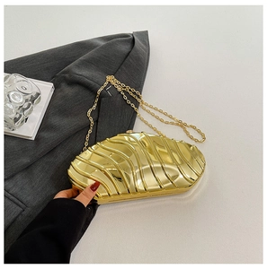 Detailed view of golden acrylic evening clutch with wavy metallic texture and chain