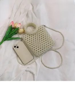 Detailed view of hand-woven white pearl handbag with beaded handles and shoulder strap