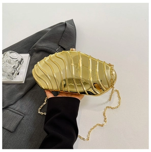 Close-up of golden shell evening clutch with wave texture and metal chain strap
