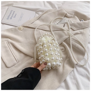 Close-up of white pearl woven bucket bag with satin drawstring liner on soft fabric