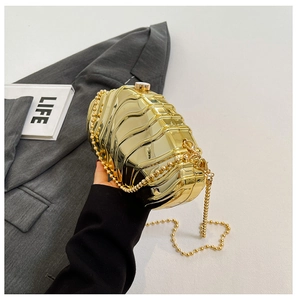 Close-up of golden acrylic evening clutch featuring unique wavy texture and beaded chain