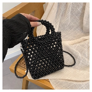 Close-up of handmade glossy black beaded handbag with woven texture and handle