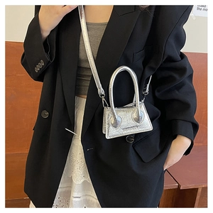 Silver mini crossbody bag with metallic crinkle texture on a model wearing black blazer