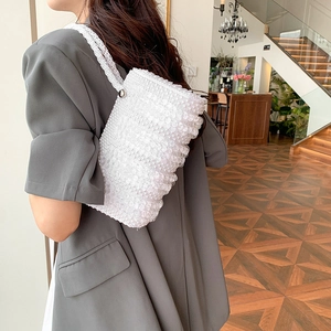 White beaded handmade pearl pillow bag for women shown as stylish shoulder bag on model