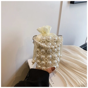 Close-up of white pearl bucket bag with drawstring liner and elegant pearl chain strap