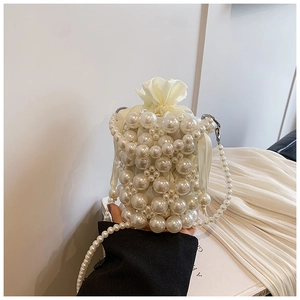 Detail of woven faux pearl bucket bag with cream drawstring liner and elegant pearl chain