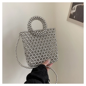 Close-up of bright silver beaded handbag featuring round handle and metal chain strap