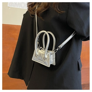 Detail of silver mini handbag with crackle texture and metal hooks on black blazer