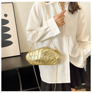 Detail of gold metal evening clutch with wavy shell texture and delicate bead chain