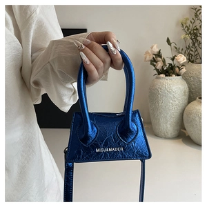 Detailed macro shot of a mini blue handbag featuring metallic textured leather and handle