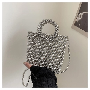 Close-up of silver beaded handbag with round handle and detachable chain strap