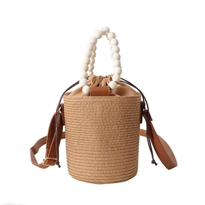 Handmade woven bucket bag with white wooden bead handle and leather shoulder strap