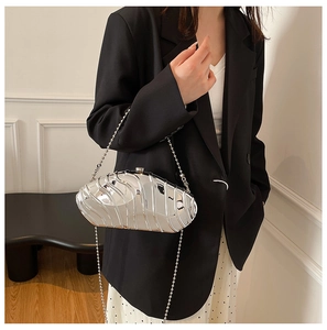 Polished silver irregular wave evening bag with metallic bead chain on a female model