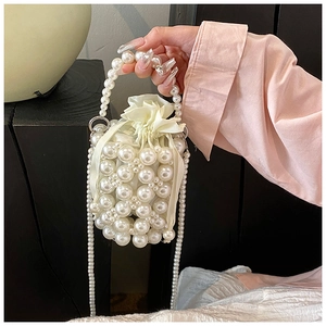 Detail of woven faux pearl bucket bag with cream satin drawstring lining and strap
