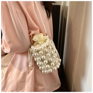 Detail of woven bucket bag featuring large pearls and satin drawstring closure with strap