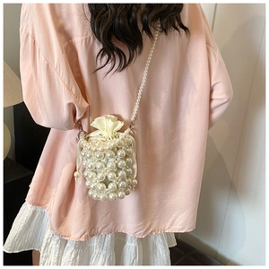 Detail of woven faux pearl bucket bag with cream drawstring liner and pearl shoulder strap