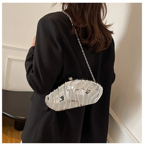 Silver metallic ripple hardshell clutch bag with chain strap shown on model's shoulder