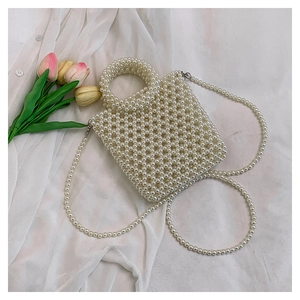 Detailed macro shot of a white pearl woven handbag with fixed handle and shoulder strap