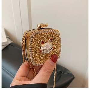 Detail of gold evening clutch featuring a fox head clasp and sparkling crystal surface