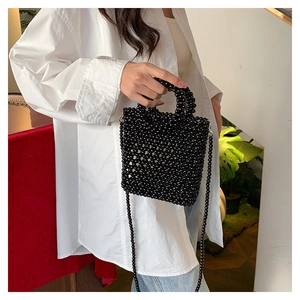 Detailed view of hand-woven black beaded square handbag with handle and shoulder strap