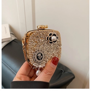 Detailed close-up of golden evening clutch with camellia flower and pearl charms