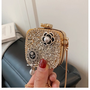 Close-up of golden clutch featuring sparkling rhinestones and camellia floral charms