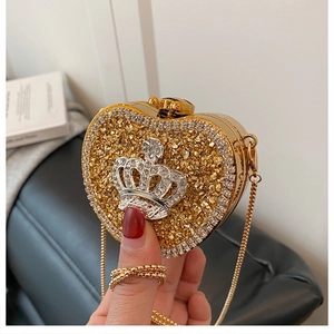 Detailed close-up of gold heart-shaped evening bag with a sparkling diamond crown motif