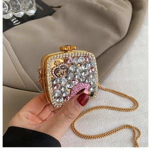 Detail of gold rhinestone evening bag with pink lips, crown motif and chain strap