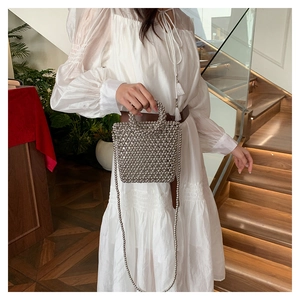 Detailed view of handcrafted silver beaded crossbody bag with woven texture on white dress