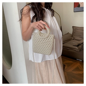 Close-up of a handmade white pearl woven mini bag with beaded handle and shoulder strap