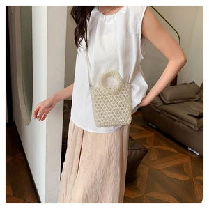 Detailed view of elegant white pearl woven handbag with top handle and matching shoulder strap